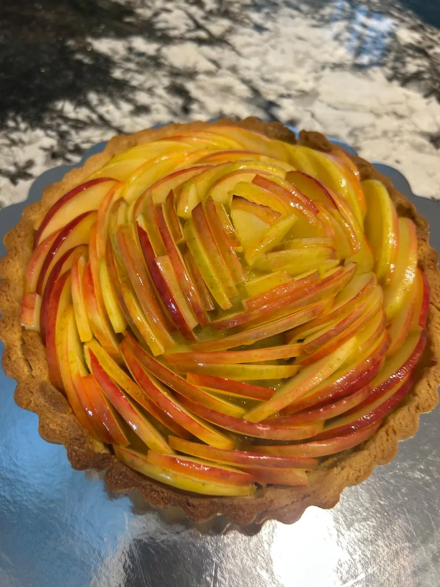 Ali's apple rose tart — paper-thin slices of apple arranged in a concentric spiral on a buttery shell, glazed.