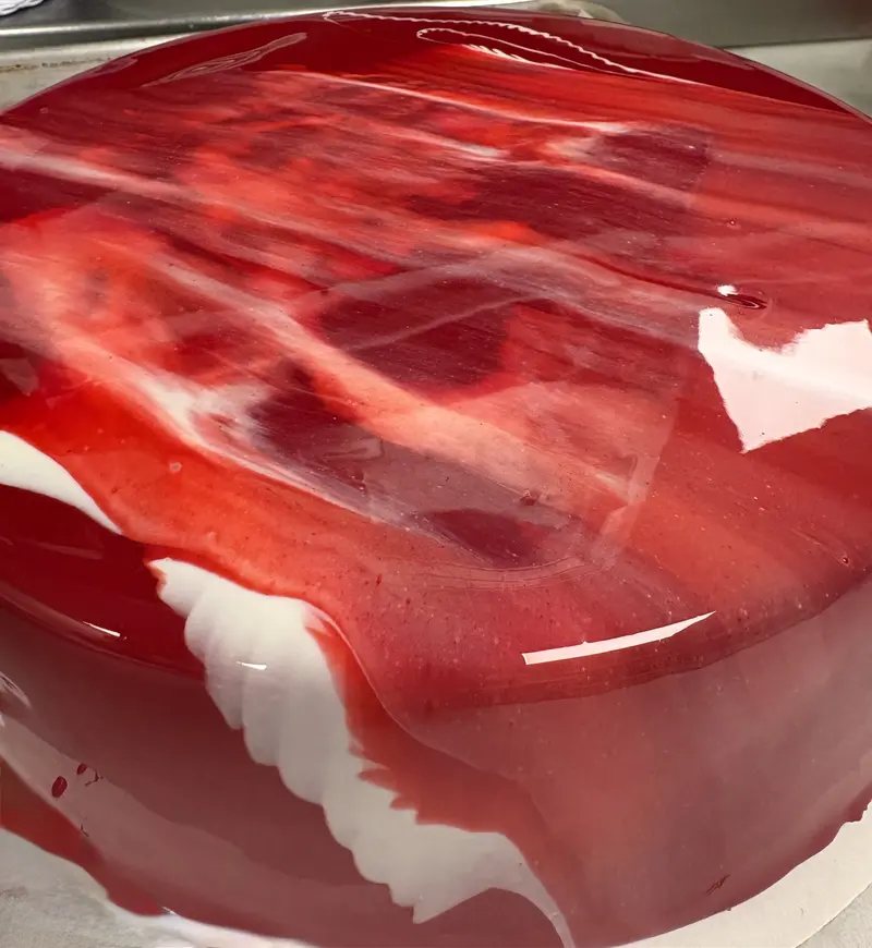 Ali's mirror-glaze Fraisier — strawberry mousseline cake finished with a high-gloss red-and-white marbled mirror glaze, viewed from the side.