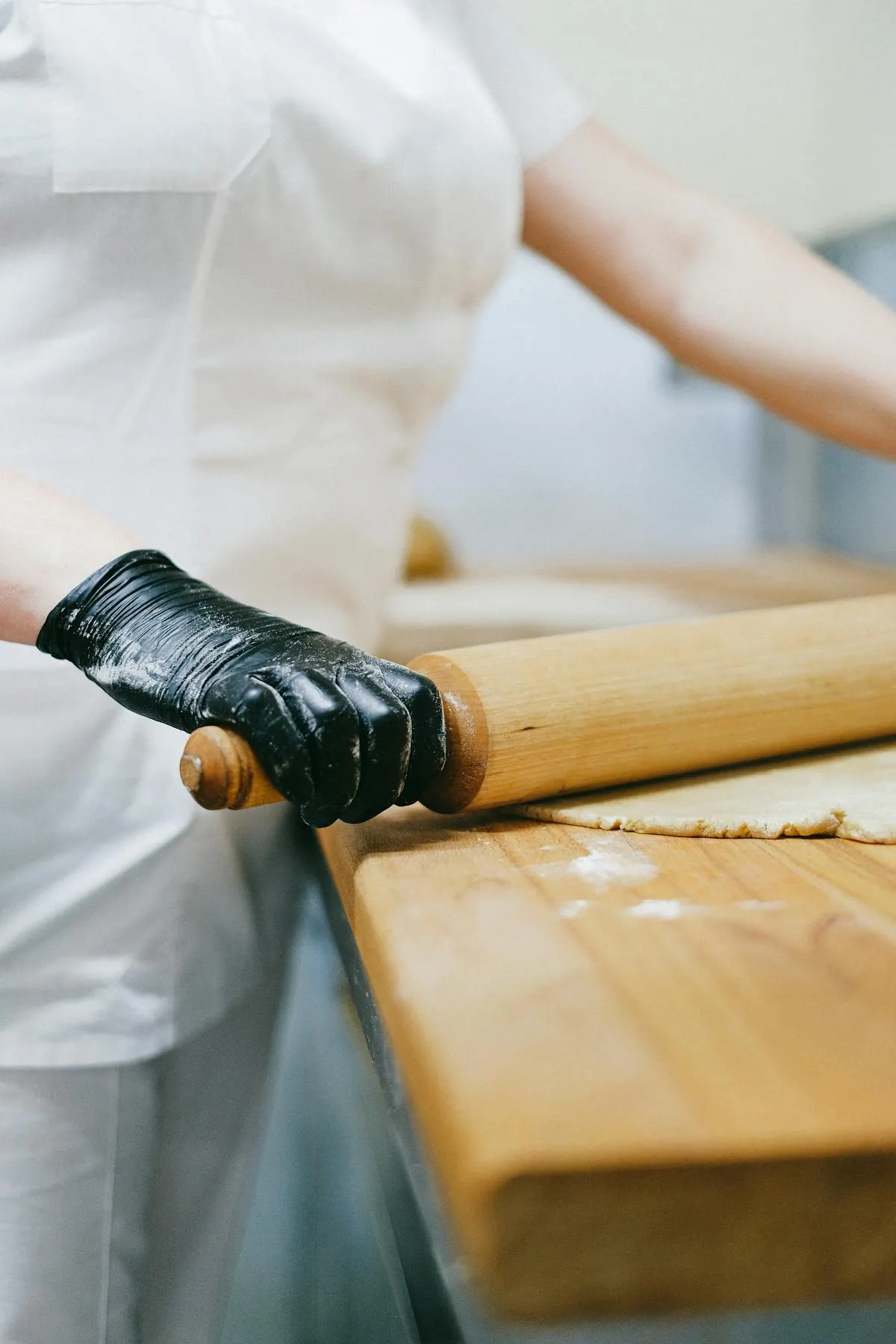 A pâtissier's hands rolling dough on a marble surface — the unglamorous part of the job that tells you everything about the work.