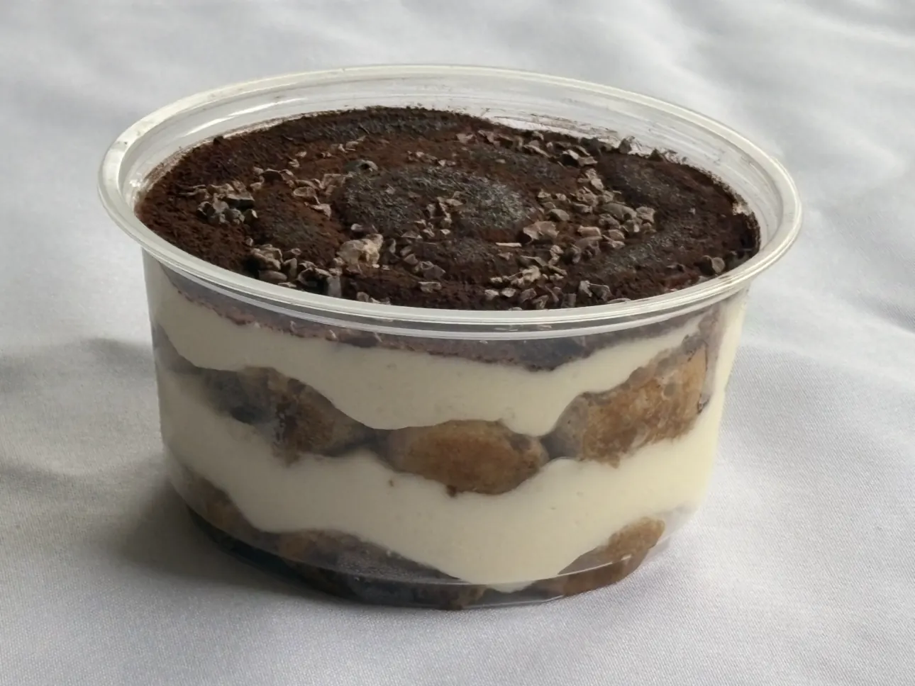 The same tiramisu seen from the side, the biscuit and cream layers visible through the cup.